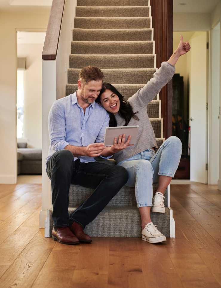 Pareja sentada en las escaleras de su casa nueva