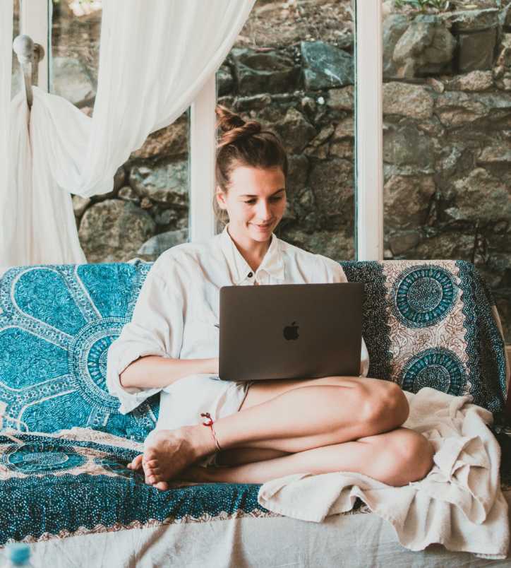 Chica sentada en el sofá trabajando con un MacBook