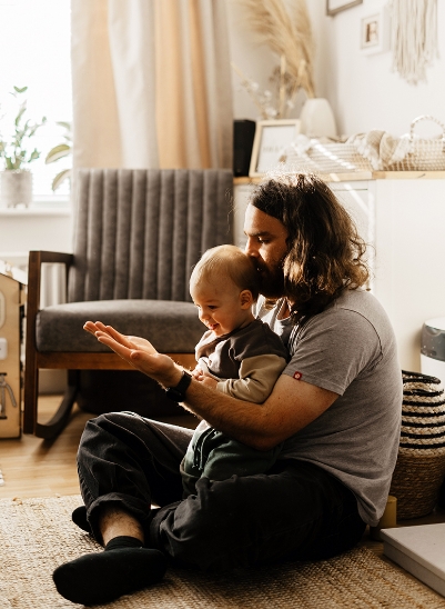Padre con el pelo largo jugando con su hijo de dos años en el salón de casa